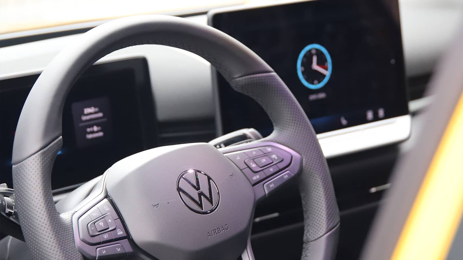 Detailaufnahme des VW T-Roc Multifunktionslenkrads mit VW-Logo, Tasten und Schaltwippen im modernen Cockpit der Fahrschule Zamzow.